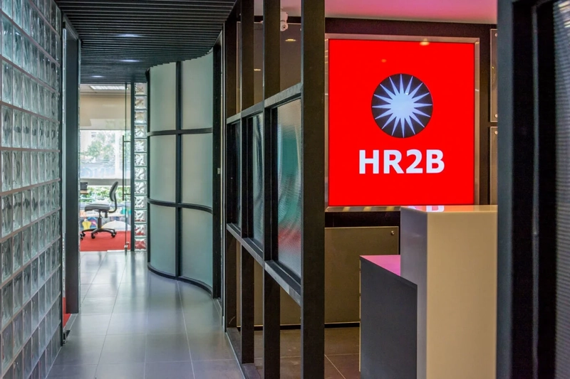 Quầy lễ tân HR2B với bảng logo đỏ, nơi cung cấp dịch vụ thuê ngoài nhân sự từ năm 2003