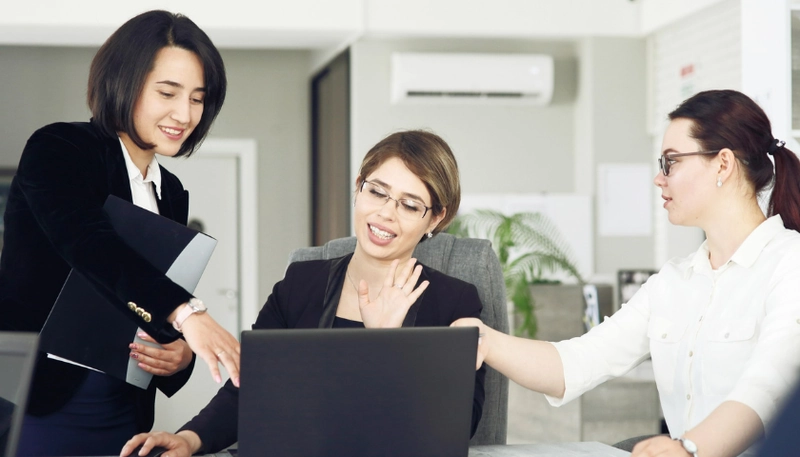 Nhóm nhân sự trao đổi bên laptop, minh họa dịch vụ nhân sự thuê ngoài cho ngân hàng và công nghệ